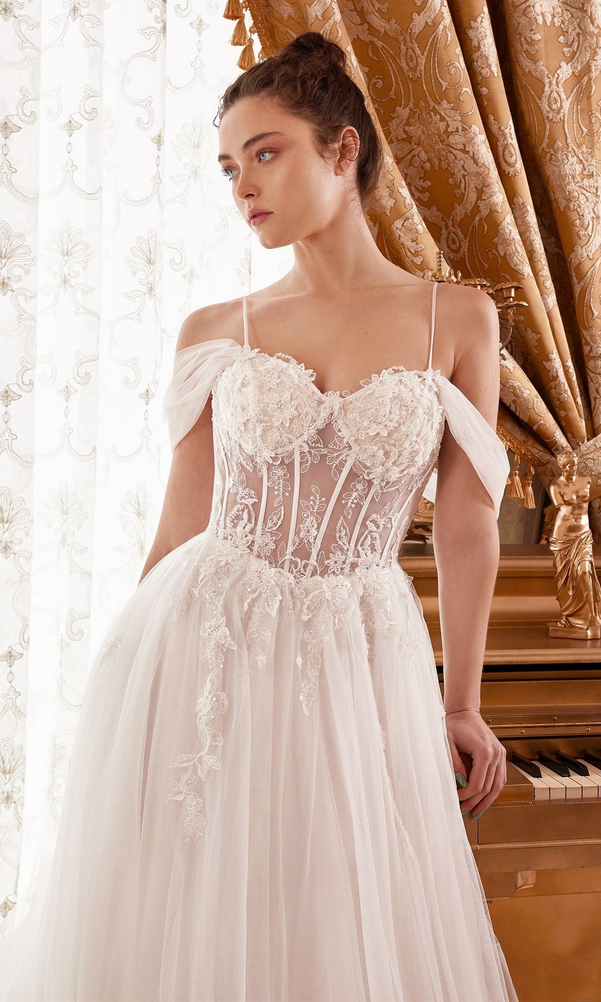 A woman in the Off-White Sheer-Bodice Long Ball Gown WN307 stands by a piano, with ornate curtains and delicate lace in the background.